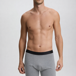 Man wearing gray boxer briefs with a black waistband on a plain background