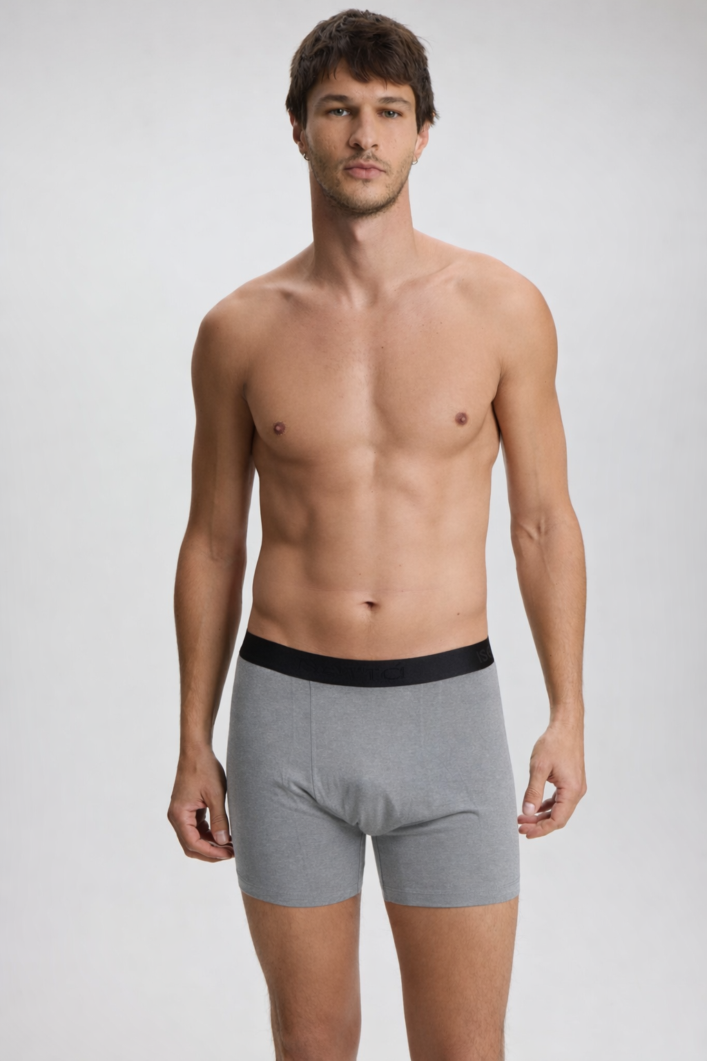 Man wearing gray boxer briefs with a black waistband on a plain background