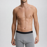 Man wearing gray boxer briefs with a black waistband on a plain background