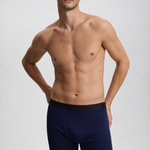 Man wearing navy blue boxer briefs on a light gray background