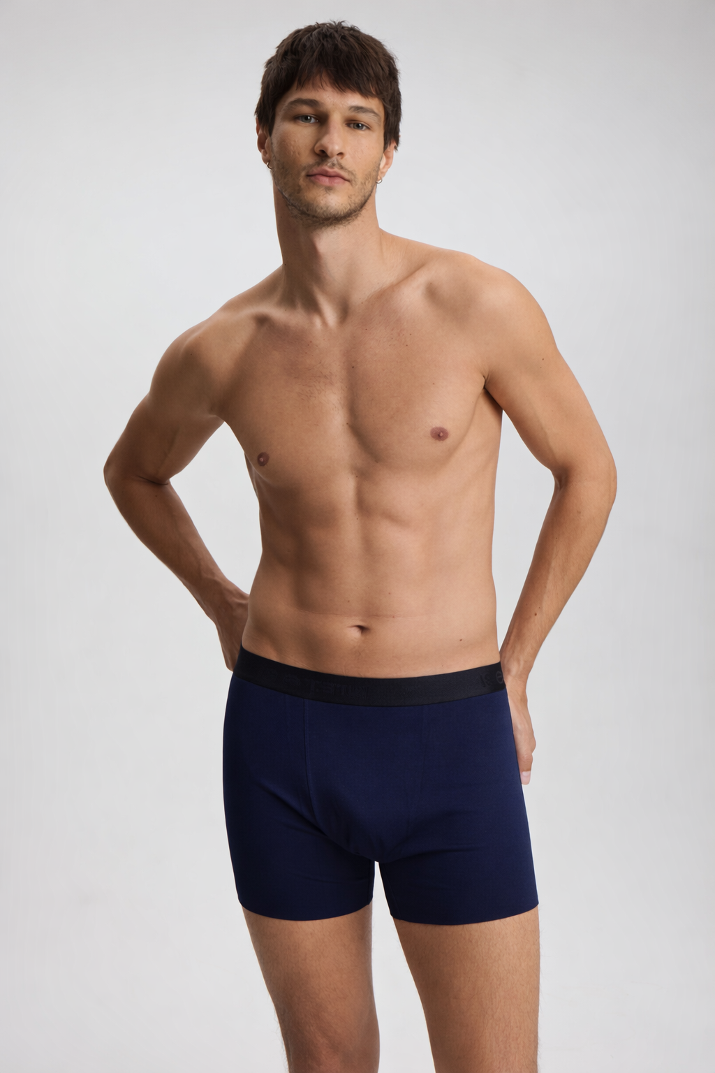 Man wearing navy blue boxer briefs on a light gray background