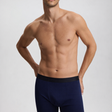 Man wearing navy blue boxer briefs on a light gray background
