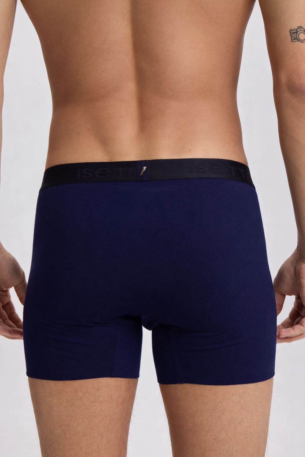 Navy blue boxer briefs worn by a person on a light gray background