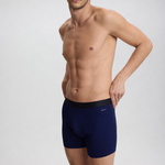Man wearing navy blue boxer briefs on a light gray background