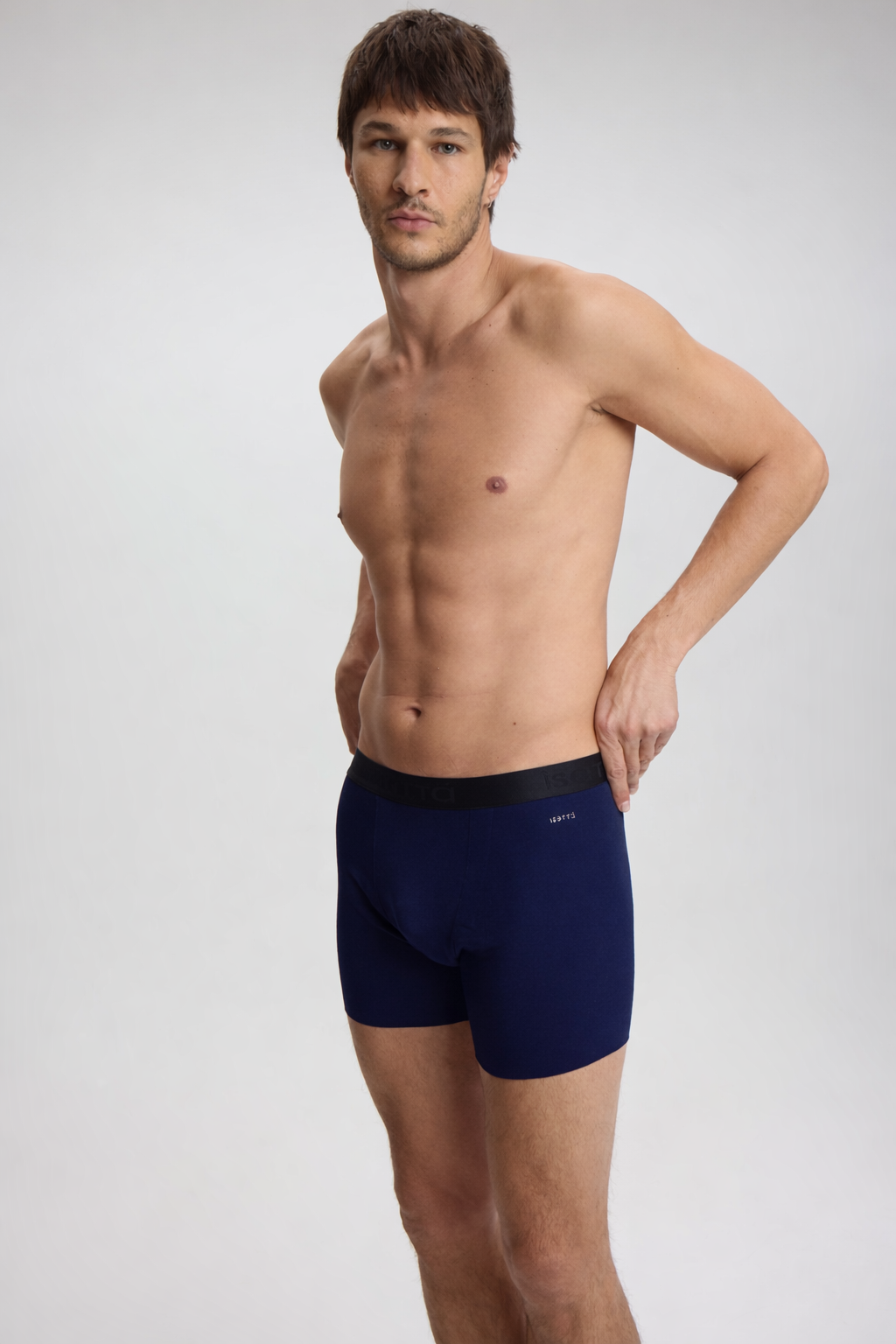 Man wearing navy blue boxer briefs on a light gray background