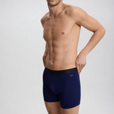Man wearing navy blue boxer briefs on a light gray background