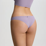 Person wearing a matching lavender sports bra and underwear set on a light gray background
