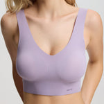 Woman wearing a light purple bralette against a plain background