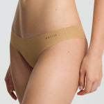 Person wearing a beige bra and underwear set on a plain background