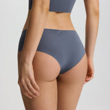 Person wearing a gray sports bra and high-waisted underwear set on a plain background