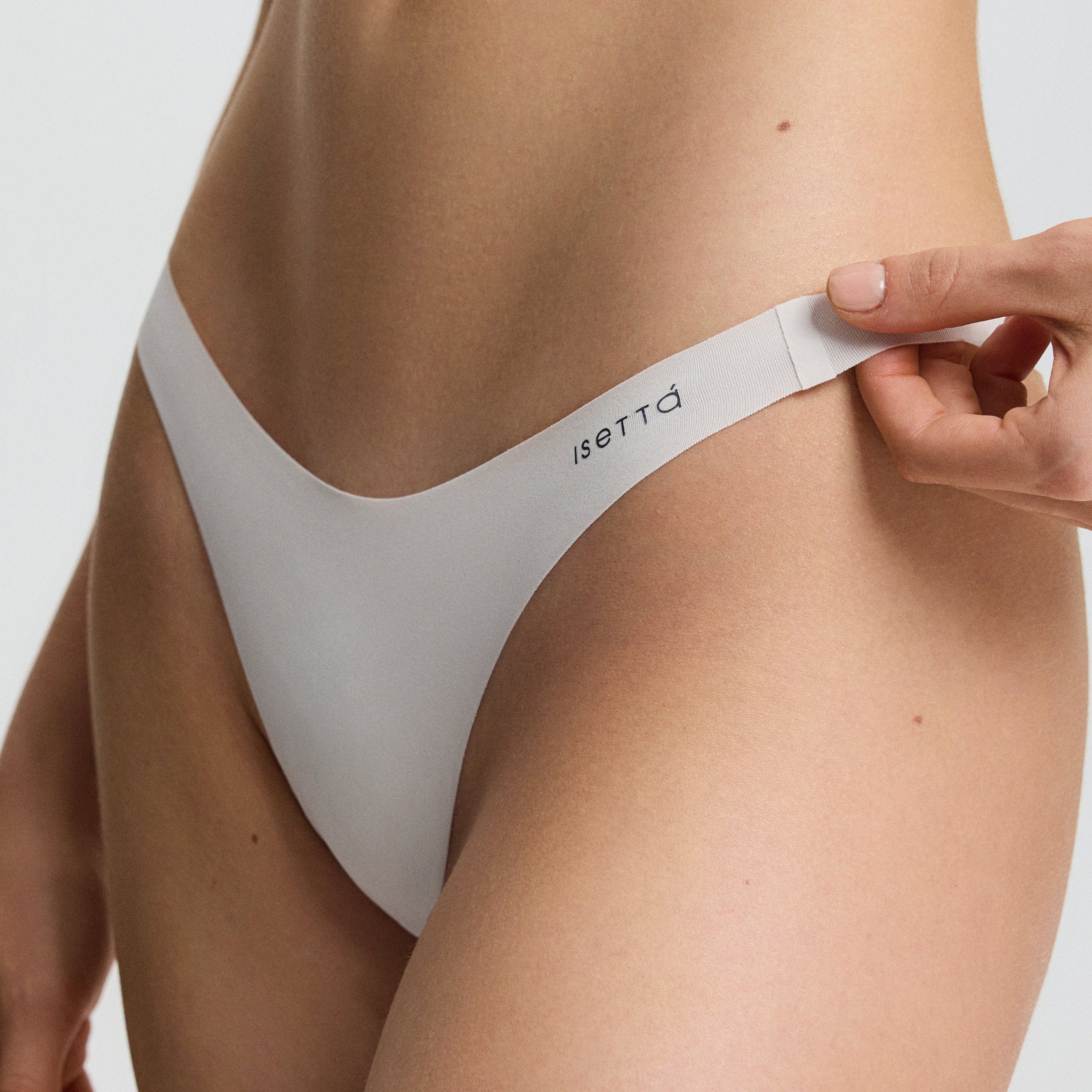 Person wearing a white thong with a visible brand logo on a plain background