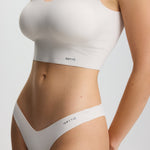 Person wearing a white sports bra and underwear set on a light gray background