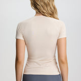 Woman wearing a beige t-shirt and gray underwear on a plain background